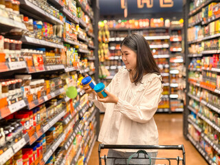woman is shopping in a grocery store and is holding two blue containers