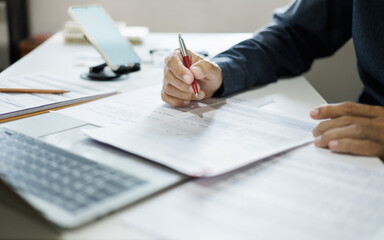 asian businessman working on desk reading and checking financial documents and business contract before sign in contract