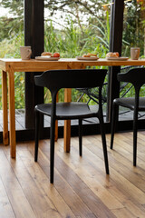 Photo showing two chairs at a breakfast bar with plates of food set near a large window, highlighting a bright, inviting space perfect for casual meals with abundant natural light

