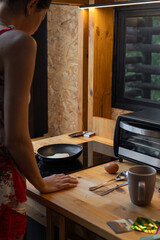 Creative photo showing a young woman lying on her bed cooking an egg in a frying pan, merging...