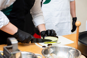Chef slicing eggplant in professional kitchen.