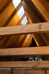 Slim wooden beams create a graceful, triangular roof design inside a tropical glamping cabin. Their...