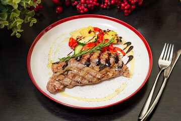 Grilled steak with vegetables and rosemary garnish.