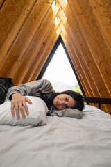 A close-up view of a young woman sleeping peacefully, hugging a soft pillow close to her chest inside a warm, rustic glamping tent filled with gentle natural light.

