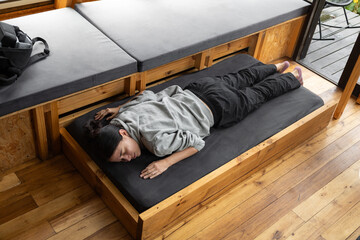 A calm young woman sleeps face down on a wooden drawer bed inside a luxury glamping tent, blending rustic charm with modern comfort and peaceful outdoor relaxation.








