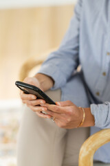 torso of female entrepreneur in button down shirt holding her iphone