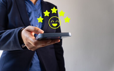  Close-up of a business woman's hand using a smartphone with a smiley face and five-star icon,...