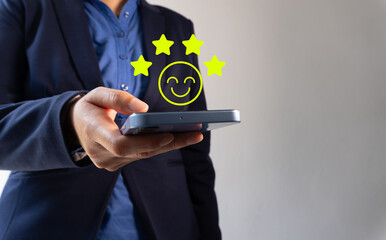 A businessman's hand using a smartphone with a smiley face and a four-star icon, indicating a...
