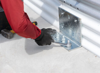 A worker is securing the plate to the concrete floor by tightening the bolts.