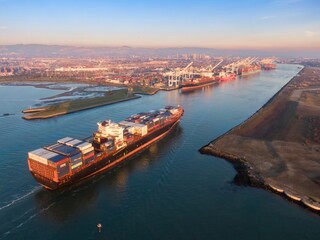 Aerial view of a container ship sailing into the Port of Oakland, California, USA. The ship is...