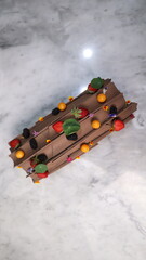 uncut chocolate roll cake topped with long chocolate chips and small fruits