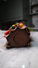 uncut chocolate roll cake topped with long chocolate chips and small fruits