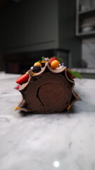 uncut chocolate roll cake topped with long chocolate chips and small fruits