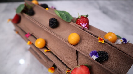 uncut chocolate roll cake topped with long chocolate chips and small fruits