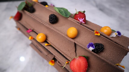 uncut chocolate roll cake topped with long chocolate chips and small fruits
