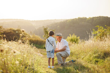 Backside photo of a little boy with his grandfather standing in a field at summer © prostooleh