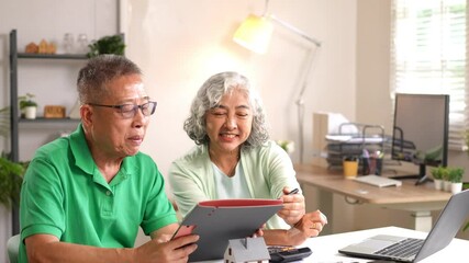 Senior man and woman using tablet together during online transaction at home office - Powered by Adobe