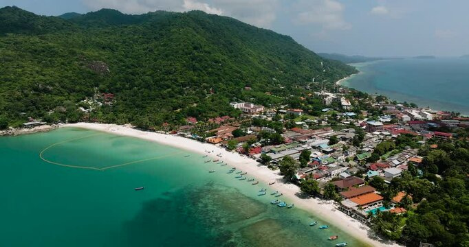 Tropical coastline featuring a village by the turquoise bay and lush mountains. Haad Rin. Ko Pha Ngan, Thailand.