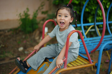 happy toddler baby girl sliding and playing at playground