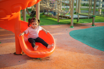 happy toddler baby girl sliding and playing at playground