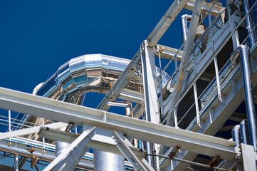 Pipelines and industrial structures at a chemical plant under a clear blue sky during the day showcasing manufacturing infrastructure