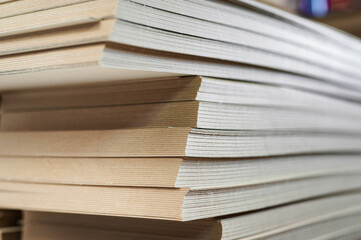 Stacks of thick paperboard ready for conversion into durable cardboard boxes at a busy...