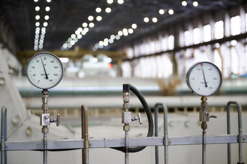 Analog pressure gauges display measurements in an industrial setting with bright lights on the...
