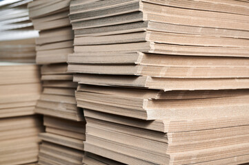 Stacks of thick paperboard ready for transformation into custom cardboard packaging solutions in a...