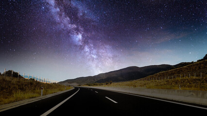Peaceful country driving road under the galaxy night with glowing stars during sunrise, 4k...