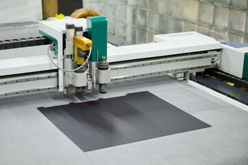 Precision cutting process using an industrial large-format CNC plotter for creative design work in a modern workshop setting