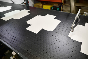 Cardboard wrap cutouts moving along conveyor in packaging factory during the gluing process for box assembly