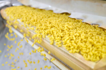 Production process in a bustling pasta manufacturing plant, showcasing vibrant yellow noodles flowing on a conveyor belt
