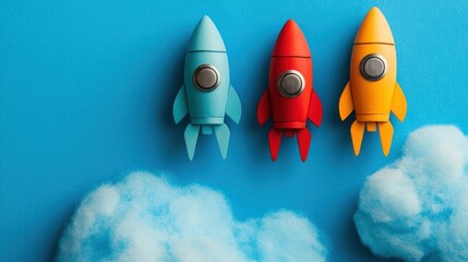 Three colorful toy rockets on a blue background with clouds
