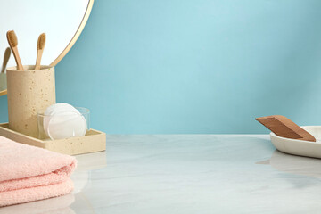 Minimal bathroom setup with toothbrush holder, pink towel, mirror and empty beige tray. Light blue...