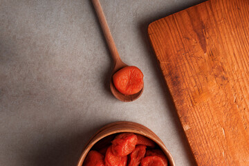 Dried apricots on wooden spoon and round wooden box. Tea time, organic tasty and healthy diet food concept photo.