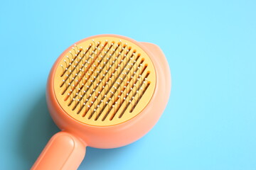 pastel orange comb on blue background, hair brush for pet