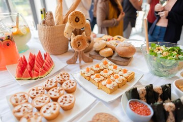 A buffet table with assorted pastries, watermelon slices, and salads. The spread includes various breads and appetizers, perfect for a casual gathering. Buffet table with delicious food.