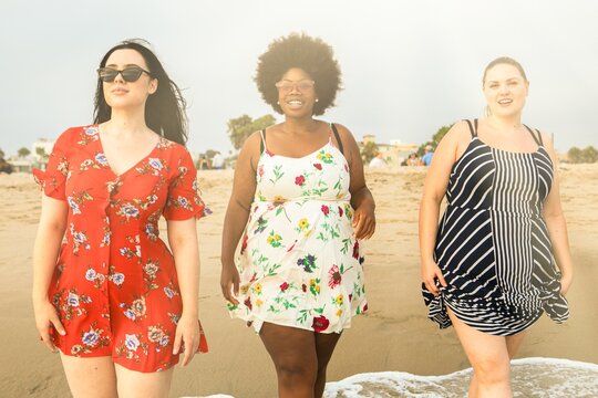Diverse confident plus size women travel to the beach. Happy curvy women at the beach. Female friends spending quality time at the beach. Diverse friends travel to the beach. - Powered by Adobe