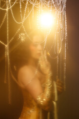 Caucasian female artist in golden Victorian-inspired corset costume, front view, dark background. Ideal for retro, Edwardian, cabaret, or theatrical performance themes.