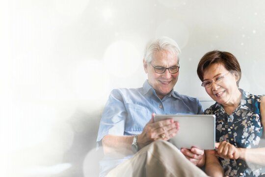 Senior couple using a digital device in a living room