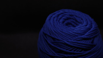 A ball of yarn in an orange color on a black background