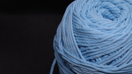 A ball of yarn in an orange color on a black background