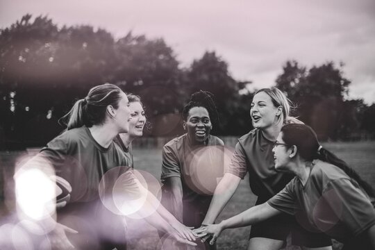 Female rugby players stacking their hands together - Powered by Adobe