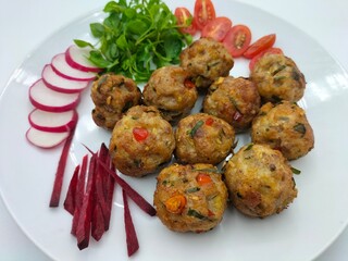 Meatballs made with homemade spiced ground chicken breast, served with beet root, radish, tomato and watercress, with a white background. tasty and extremely delicious.