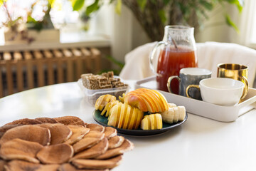 Healthy breakfast setup with pancakes, fruit slices, crispbread and tea in cozy morning home kitchen