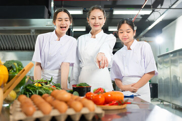 Professional Chef Mentoring Young Cooks in a Bright Kitchen, Chef and Students Learning Culinary Skills in Kitchen, Women Preparing Fresh Ingredients for Cooking Class