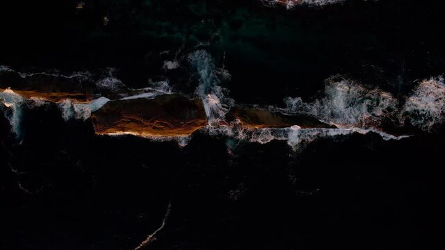 Morning sun lights a rock surrounded by shallow sea near Warden Head Lighthouse, Ulladulla NSW. Gentle waves lap the shore in this peaceful coastal drone shot showcasing nature&rsquo;s calm beauty.