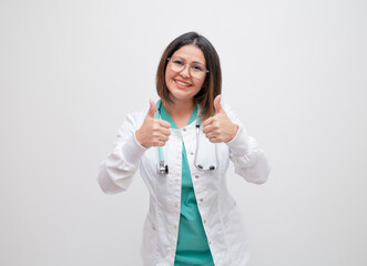 young woman doctor smiling giving thumbs up positive with stethoscope around neck and white lab...