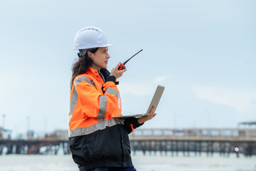 Profile view of a female engineer reporting status via radio at a logistics and shipping terminal....