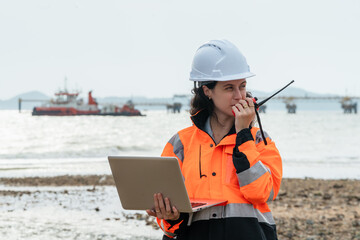 Female maritime engineer coordinating with a tugboat via radio at an offshore oil and gas terminal....